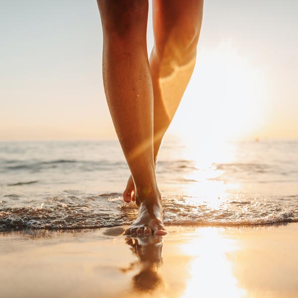 person walking on beach at sunset